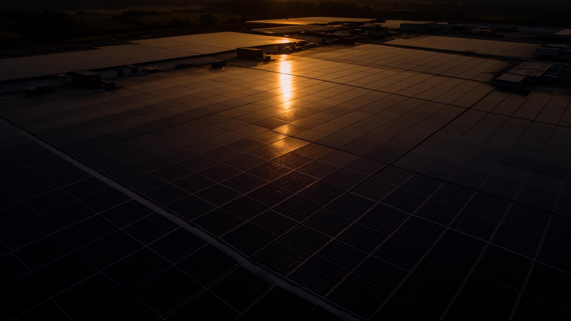 Großflächige Photovoltaik-Dachanlage in der Abendsonne aus der Drohnenperspektive